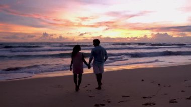 Men and women walking on the beach during sunset in Phuket Thailand. Asian women and European men walking on the beach at sunset 