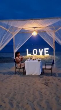 Huahin Tayland sahilinde romantik bir akşam yemeği Hua Hin 'de mum ışığında akşam yemeği, sevgililer günü konsepti. Tayland sahilinde romantik bir akşam yemeği yiyen iki erkek ve kadın. 