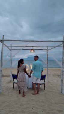 Huahin Tayland sahilinde romantik bir akşam yemeği Hua Hin 'de mum ışığında akşam yemeği, sevgililer günü konsepti. Tayland sahilinde romantik bir akşam yemeği yiyen iki erkek ve kadın. 