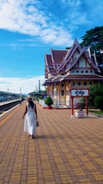 Şapkalı ve çantalı Asyalı kadın Tayland 'daki Hua Hin tren istasyonunda treni bekliyor..