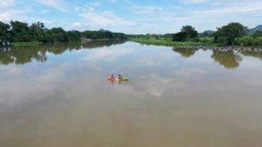 A couple of men and women in kayak on the River Kwai in Thailand. men and women peddling in a kayak on the river in Thailand