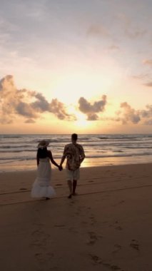 Men and women walking on the beach during sunset in Phuket Thailand. Asian women and European men walking on the beach at sunset 
