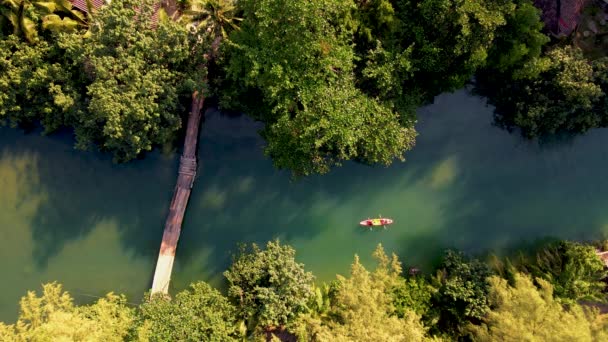 午後の日没の間にカヤックで遊んでいるカップルの男性と女性 カヤックで川の上からのドローンの眺め 熱帯島のKoh Chang Thailandの長い川でカヤックの人々 高品質4K — ストック動画