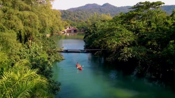 午後にカヤックを漕いでいるカップルの男性と女性 熱帯の島のコチャンタイの長い川でカヤックの人々 日没時の川でのドローンビュー — ストック動画