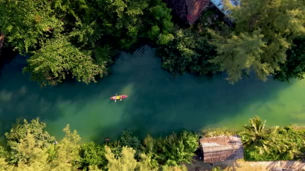 午後にカヤックで遊んでいるカップルの男性と女性の上からのドローンの眺め 熱帯の島の長い川でカヤックの人々 Koh Chang Thailand — ストック動画