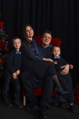 Noel ve Noel için Noel ağacındaki zarif anne ve baba ve çocukların portresi. Noel elbisesi, anne baba ve çocuklar Noel ağacının yanında.