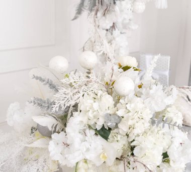 Beyaz çiçeklerin, ladin dallarının ve beyaz noel balolarının Noel aranjmanı