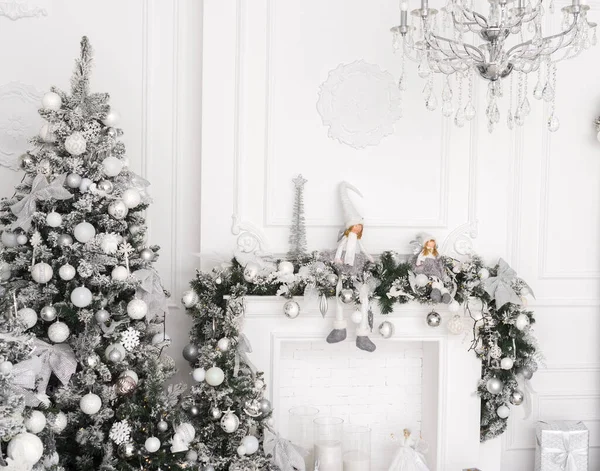 Beyaz süslemeleri ve beyaz şöminesi olan bir Noel ağacı. Beyaz gümüş renkli dekor, Noel ve Yeni Yıl için açık renk.