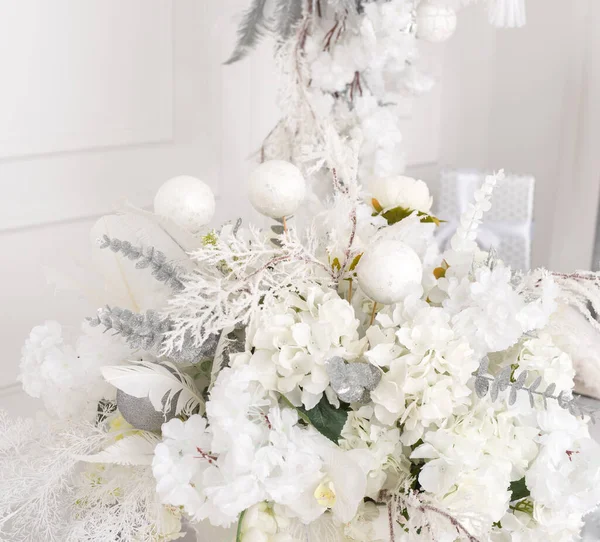 Beyaz çiçeklerin, ladin dallarının ve beyaz noel balolarının Noel aranjmanı