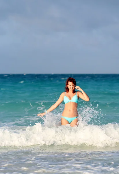 Smiling young redhead woman standing in the ocean wave — Stock Photo, Image