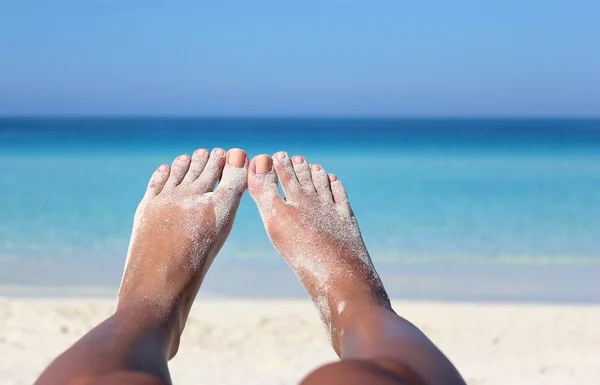 Piernas de mujer que ponen om la orilla del mar en el sol de verano — Foto de Stock