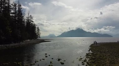 Güçlü dağlar ve ormanlar denizi çevreleyen, alçak bir kuşun gözünden ılık bir sonbahar gününde, bulutlu gökyüzünü gören açık havada.