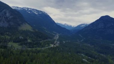 Bulutlu havada, kozalaklı ormanlarla tepelerin yakınındaki uçurumların üzerinden uç.