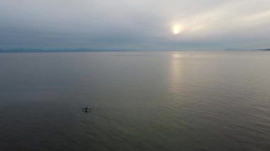 Vancouver 'da günbatımında sakin deniz manzarası ve kanolardaki çift.