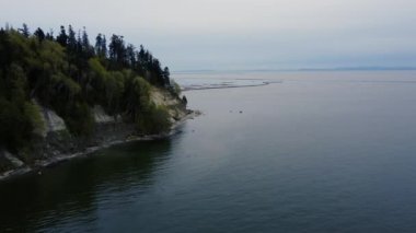 Kanada 'da günbatımında sakin denizin üzerinde dik kıyı boyunca uç.