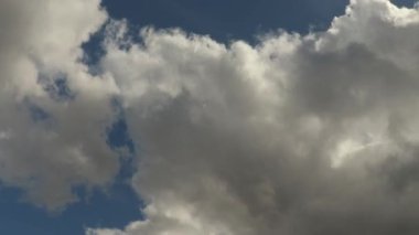 Mavi gökyüzünü kaplayan beyaz ve gri bulutlar zaman ayarlı 4K