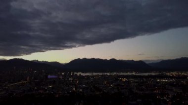 Aerial view of business district in Canada at dusk with mountains on background