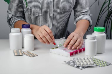 Hapları hap kutusuna koyan yaşlı kadının elleri. İlaç konteynırı. Ağrı kesici ve hastalık tedavisi için ilaç kullanan bir kadın. Hasta, emekli, uyuşturucu bağımlısı kadın. Sağlıklı yaşam için günlük vitaminler