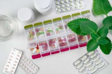 Haplarla dolu iki haftalık ilaç kutusunun üst görüntüsü. Mavi hap kutusu, hafif mermer masanın üstünde. İlaç kutusunu aç ve içinde haplar ya da vitaminler olan kutuları aç. Yaşlı hasta için ilaç kutusu