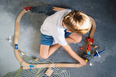 Çocuk oyuncak ahşap yolda oynuyor. Üst Manzara. Çocuk odasında oyuncak trenle oynuyor..