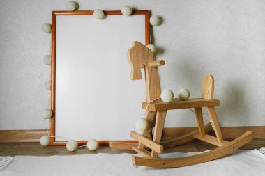 Çocuk odasındaki resmin bir kopyası. Tahta at ve örgü oyuncaklar. Bebek odasının içi bej renkli..