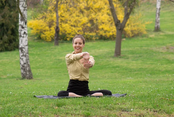 Streching flicka i parken och leende — Stockfoto