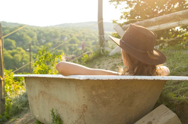 Sexy cowgirl sitting in bath on ranch — Stock Photo, Image