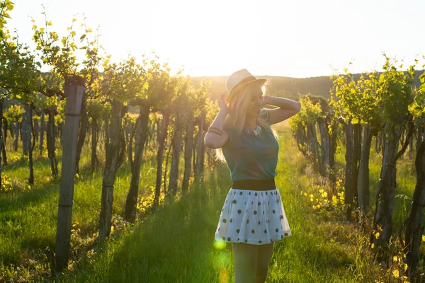 Hermosa chica de pie en el sombrero entre uvas . — Foto de Stock