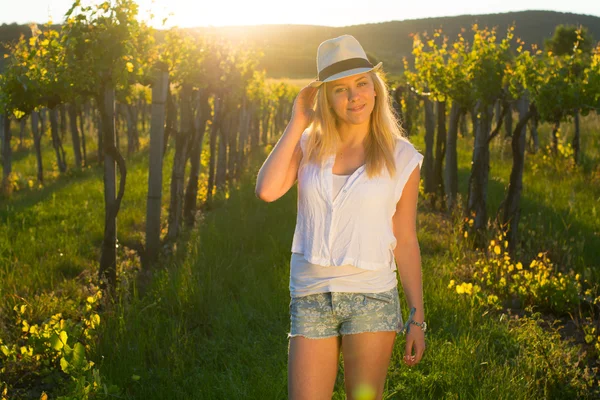 Beautiful girl standing in hat between grapes. — Stock Photo, Image