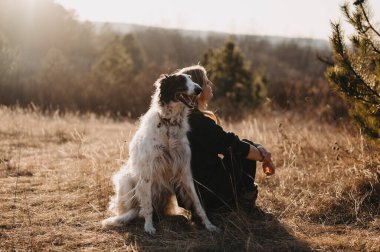 Kadın dışarıda Rus av köpeğiyle oturuyor.