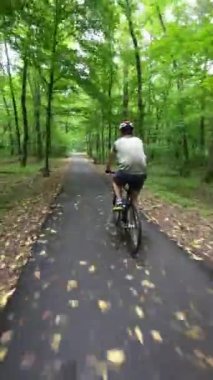 Man in protective helmet ride on bicycle in the park. Following Shot.
