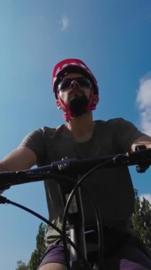 Young man in protective helmet ride on bicycle sunny summer day. Low angle view. 