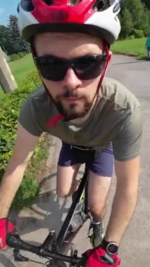Man in red helmet and red gloves ride on bicycle summer sunny day. Tracking shot.