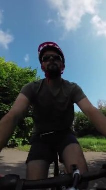 Young man in protective helmet and sunglases ride on bicycle summer sunny day. Tracking Shot.