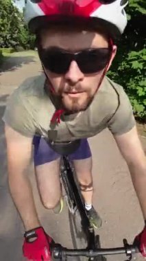 Man in red helmet and red gloves ride on bicycle summer sunny day. Tracking shot.