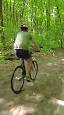 Following Shot of a cyclist who ride in a green summer forest. 