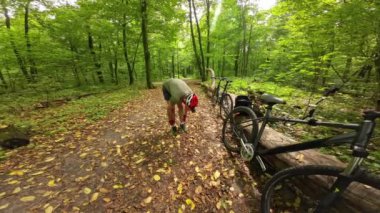 Man in a protective helmet straightens his socks before bicycle ride in the forest. Extreme sports and safety.