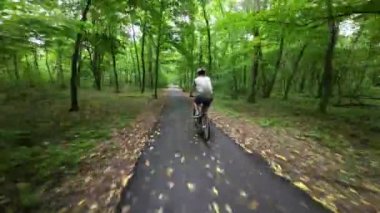 Man in protective helmet ride on bicycle in the park. Following Shot.