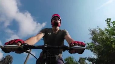 Young man in protective helmet ride on bicycle sunny summer day. Low angle view. 