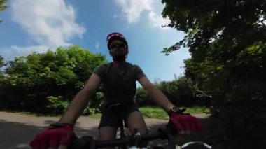 Young man in protective helmet and sunglases ride on bicycle summer sunny day. Tracking Shot.