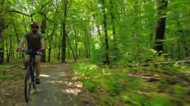 Following Shot of a cyclist who ride in a green summer forest. 