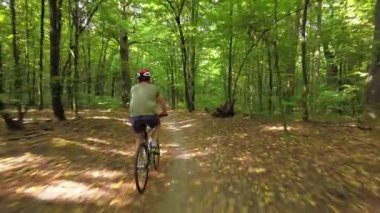 Young man in a bicycle helmet rides a bicycle through the forest. Following Shot 