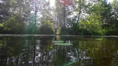 A woman is fishing on the shore of a lake on a sunny day.