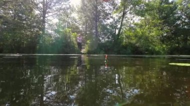 A woman casts a fishing rod on a sunny summer day.