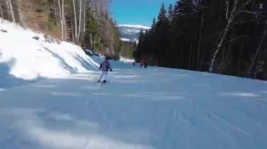 Güneşli bir günde kayak pistinde kayak yapan bir kadın. İzleme görüntüsü