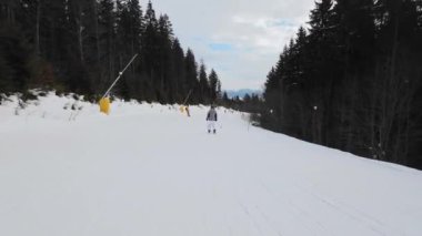 Bulutlu bir günde kayak pistinde kayak yapan bir kadın. İzleme görüntüsü
