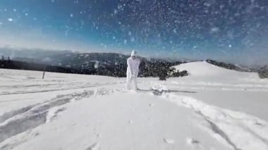 Bir kadın, dağlarda güneşli bir günde karlı bir kışın tadını çıkarır. Yavaş Hareket