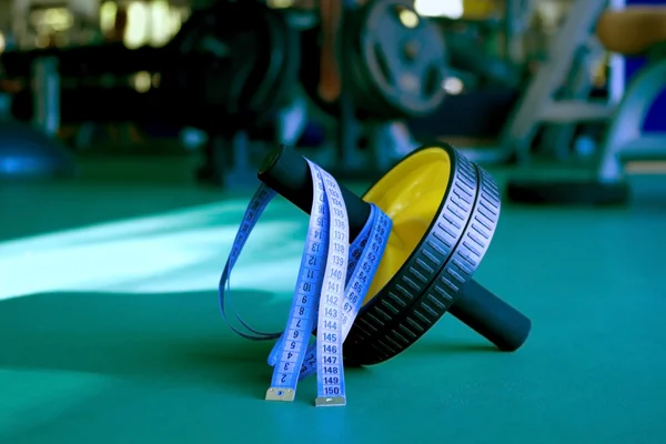 Rueda de ejercicio y cinta métrica en el gimnasio —  Fotos de Stock