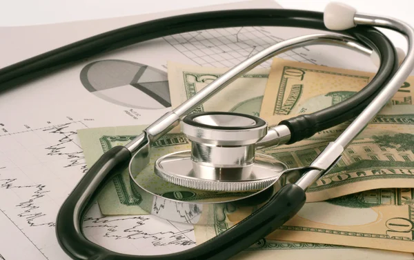 Financial graphs, money and stethoscope — Stock Photo, Image