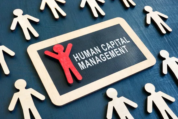 Bord met woorden Human capital management en rood beeldje. — Stockfoto
